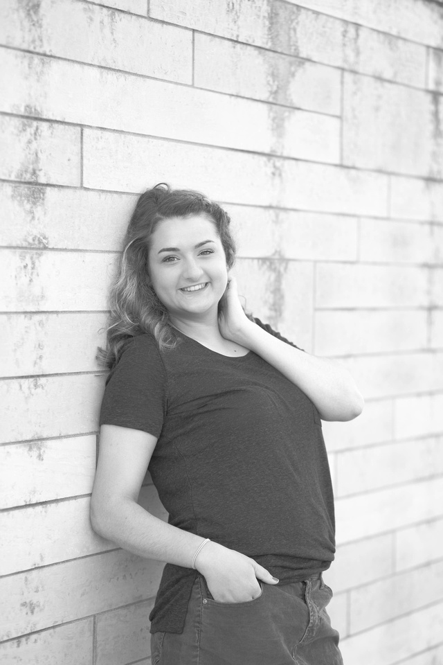 Senior photo in front of a brick wall in downtown Des Moines