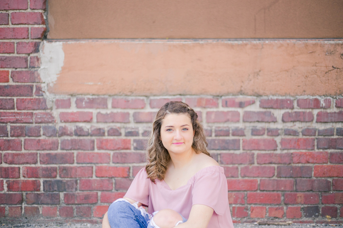 Senior photo in front of a brick wall in downtown Des Moines